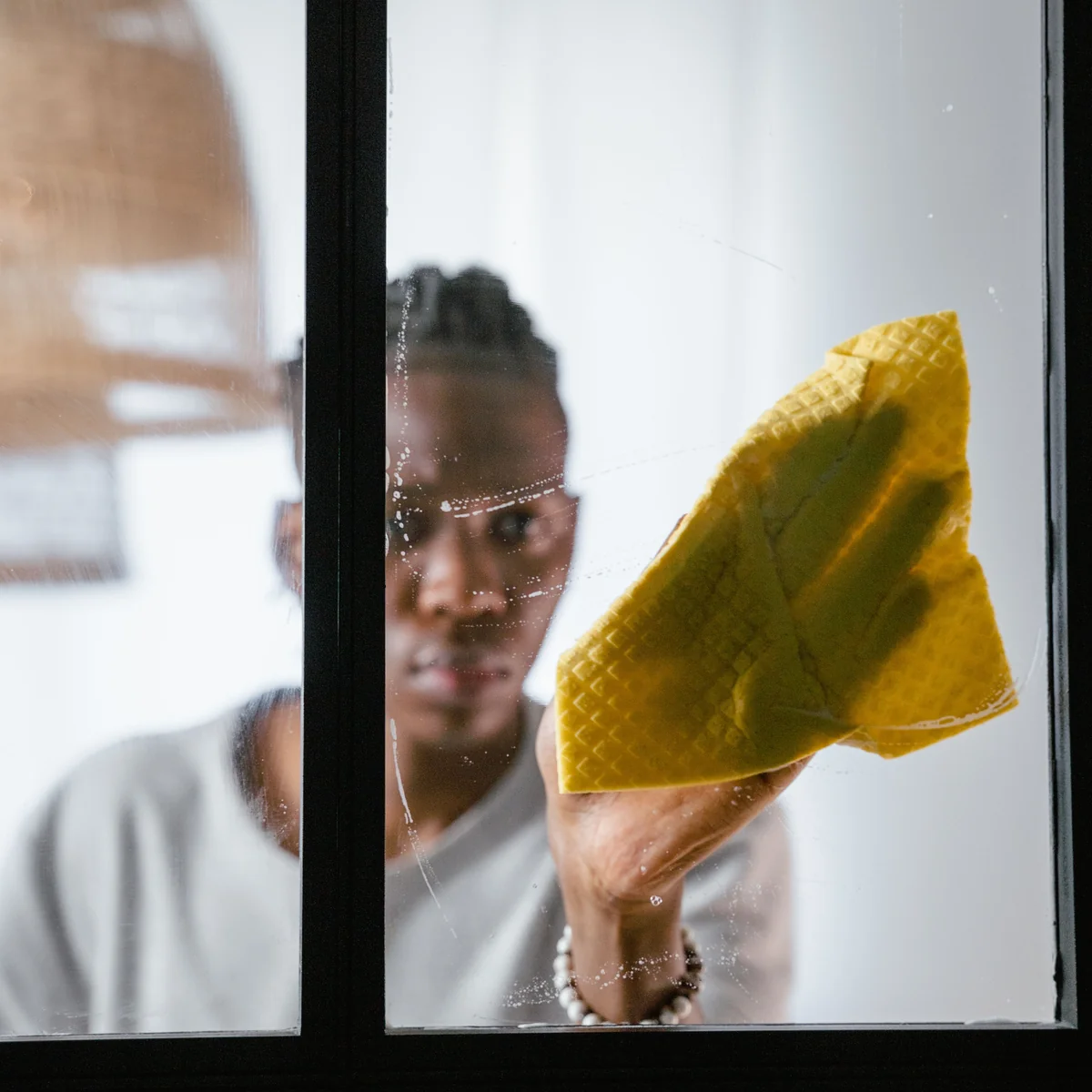 Person wiping a glass window with a reusable cloth